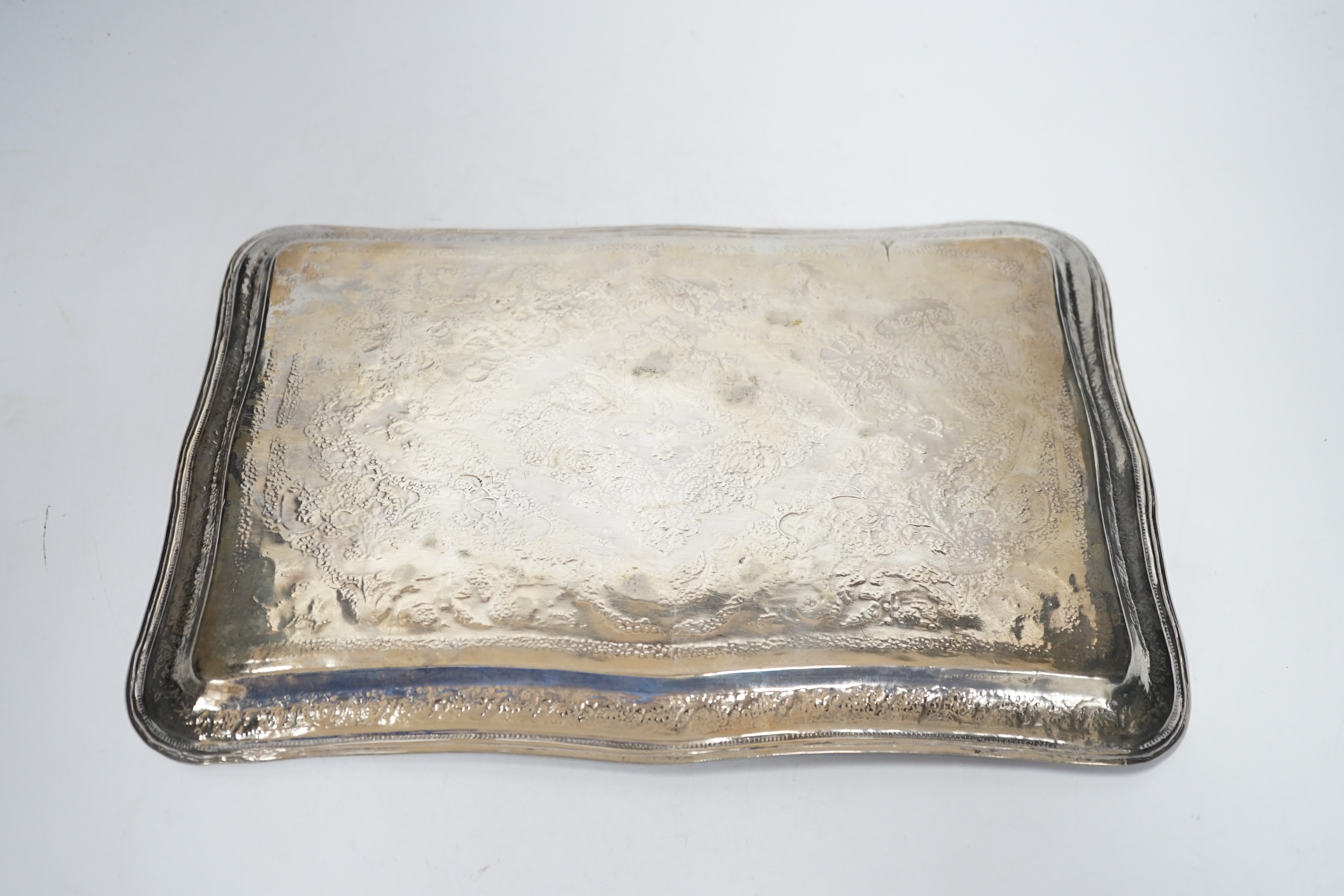 An Indian white metal dressing table tray decorated with floral motifs, 36cm